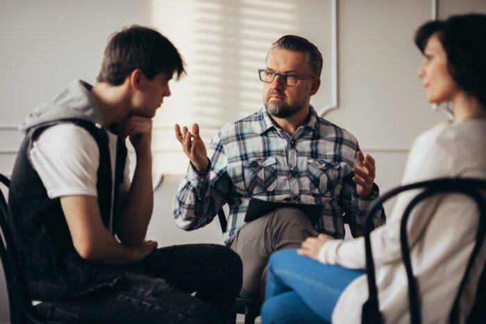 A counselor leading a session with two visible people.