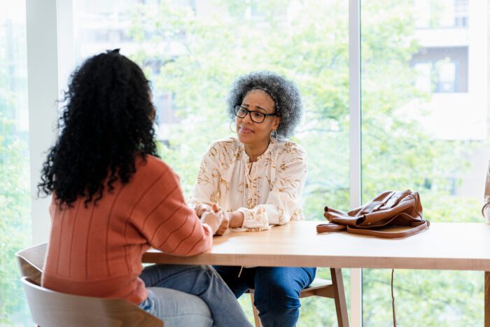 An older woman sitting at a table comforting a younger woman.