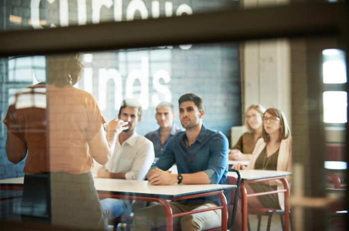 A woman stands before a small class teaching.